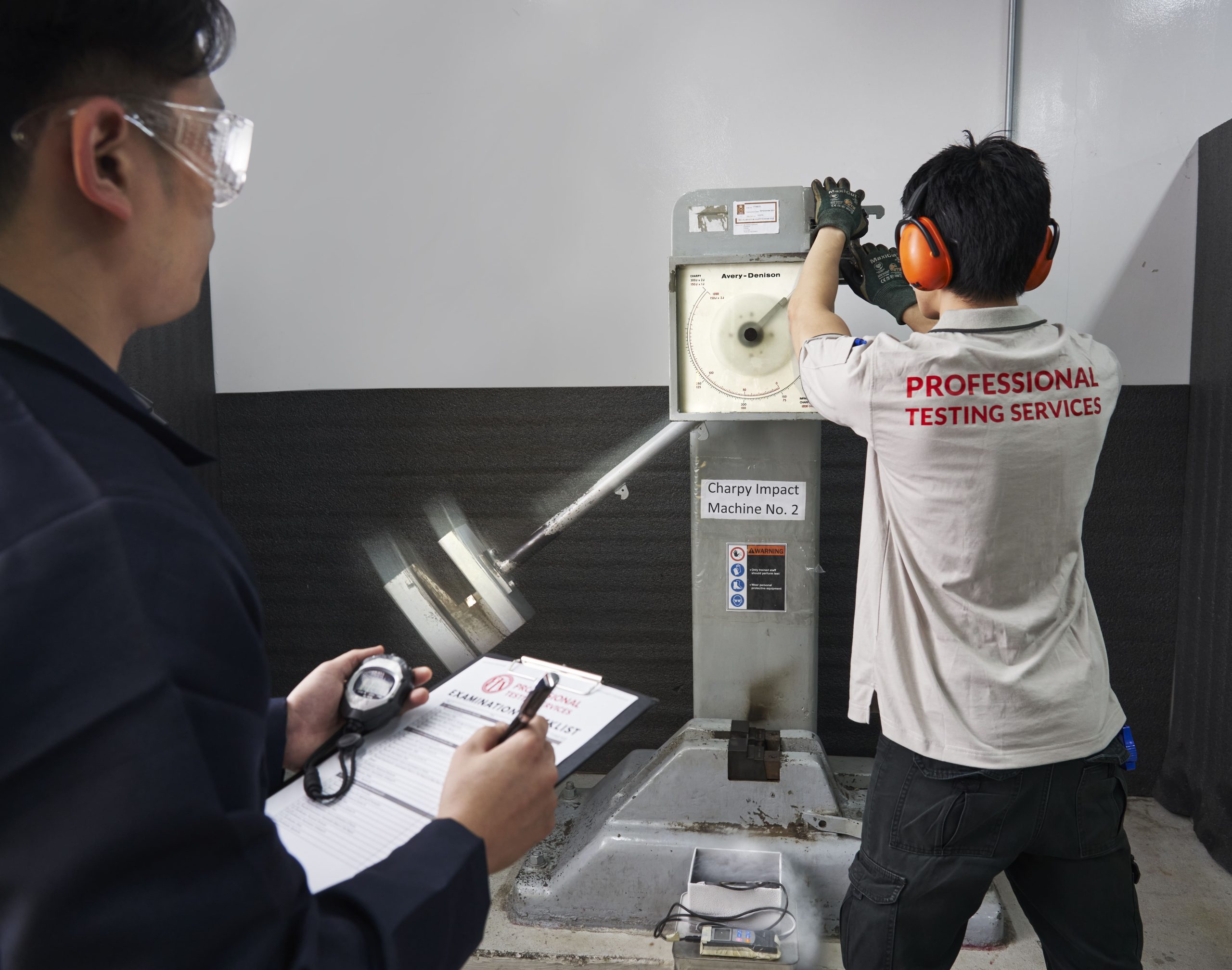 Engineers testing a sample material’s impact strength with a Charpy impact test.