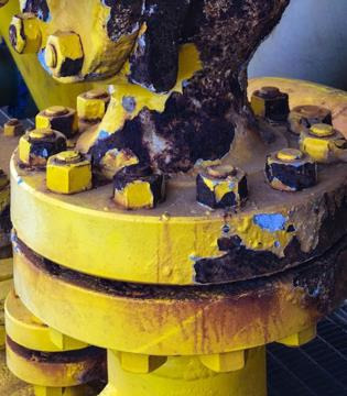 A bolted yellow flange assembly with heavy crevice corrosion damage at the fastener joints.