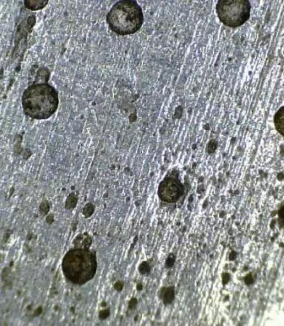 Magnified view of a metal surface with pitting corrosion cavities after a pitting corrosion test.