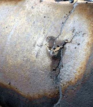 Close-up of a cracked metal surface showing corrosion damage from sulfide stress cracking.